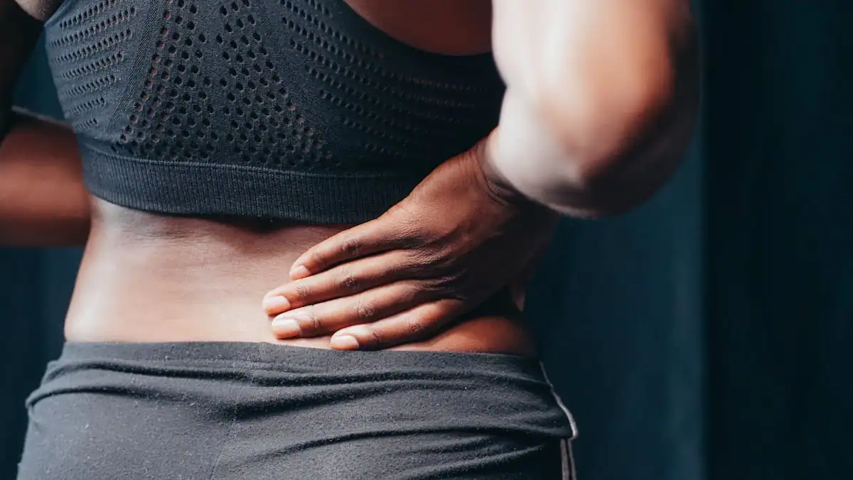 Person holding their lower back, representing the chronic pain shockwave therapy is designed to address