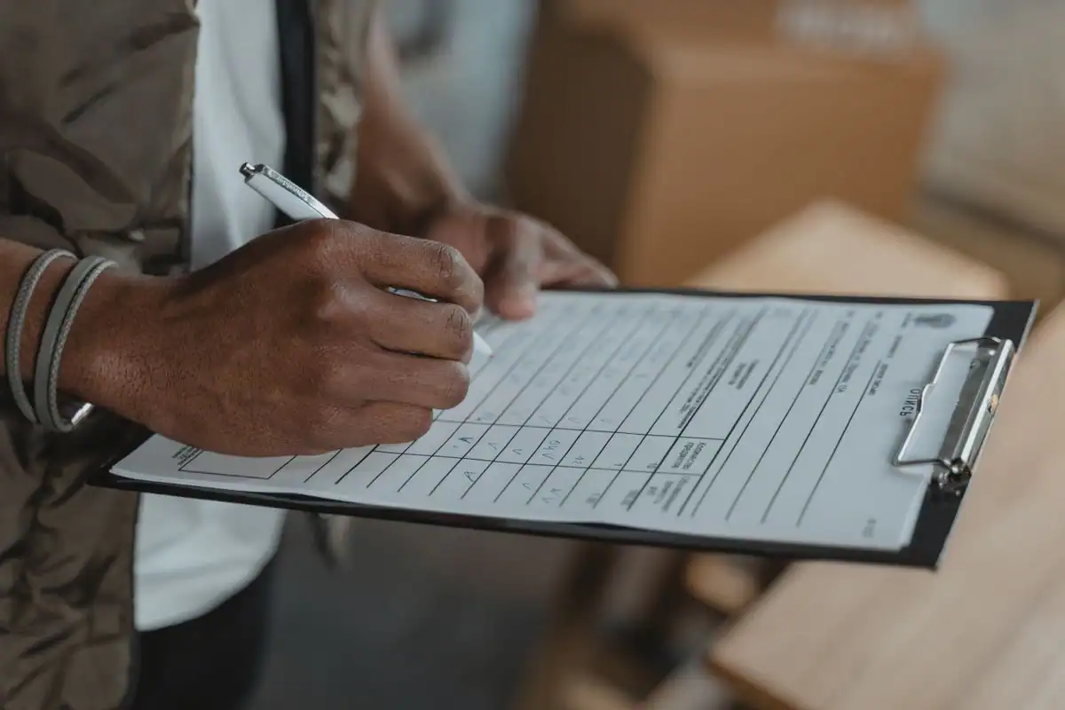 Person filling out an insurance claim form on a clipboard after a crash