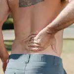 Man holding his lower back in pain, a common reason to see a chiropractor in Jacksonville
