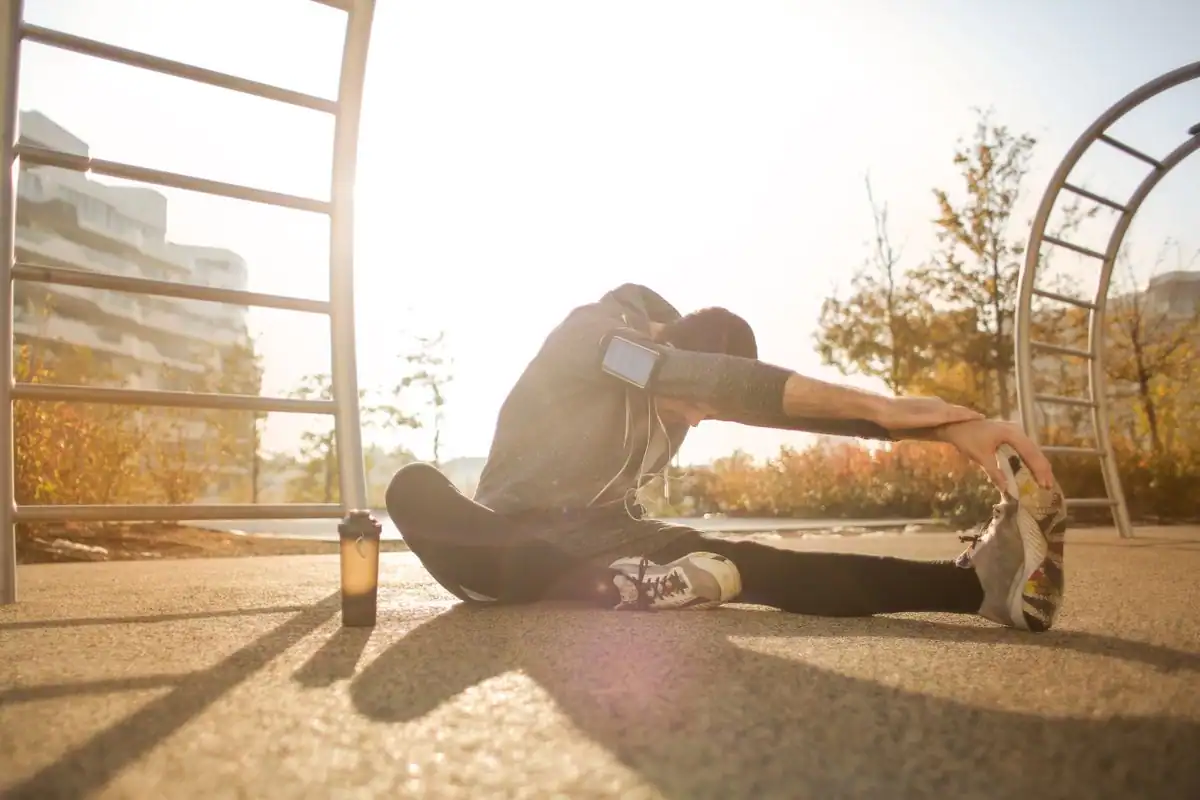 An athlete stretching his legs on an outdoor sports ground before training