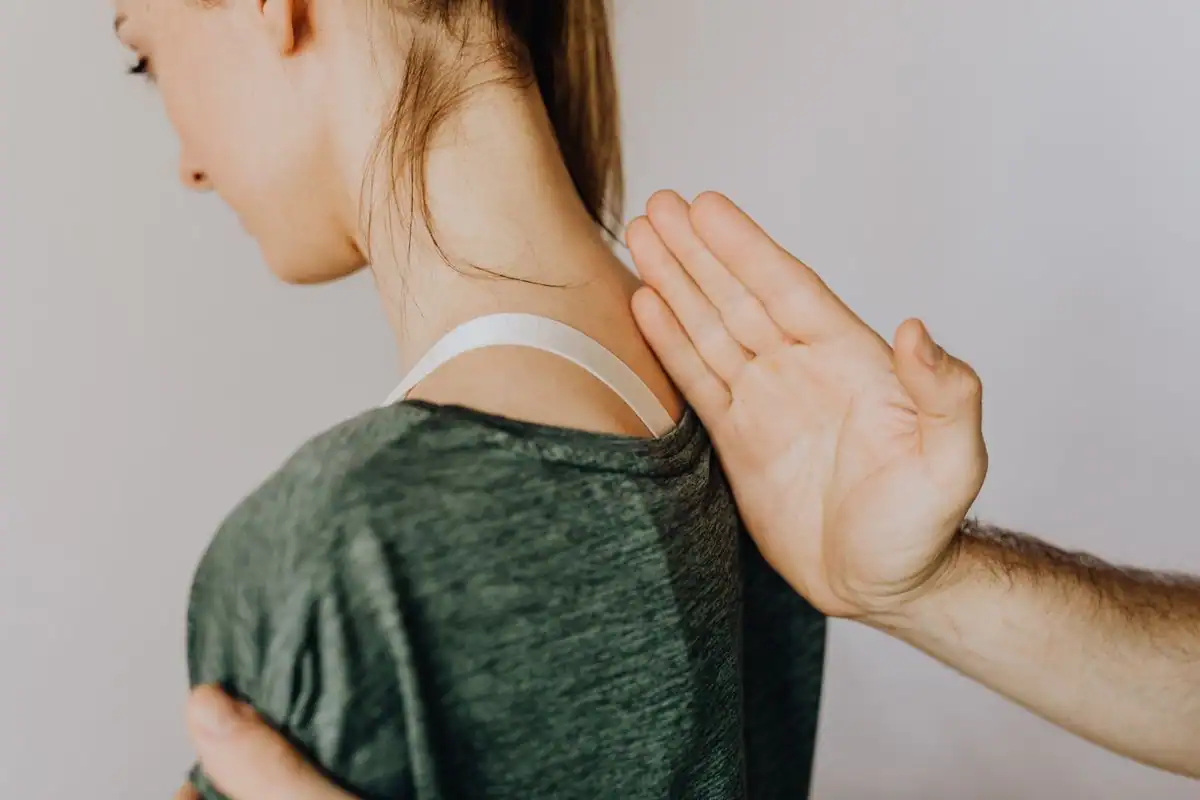 A practitioner examining the upper back and spine of a patient in a clinic