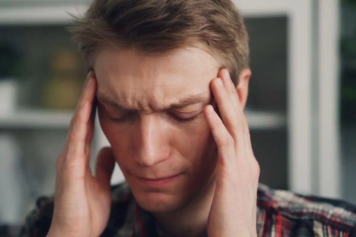 A person at a computer rubbing their temples with a worried, tired expression