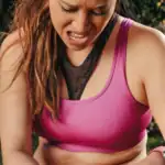 A woman in sportswear gripping her painful knee during an outdoor run
