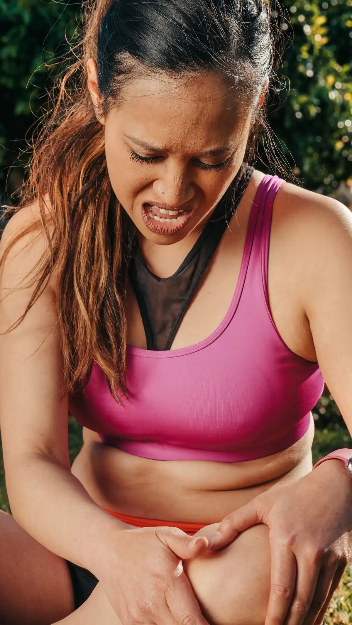 A woman in sportswear gripping her painful knee during an outdoor run