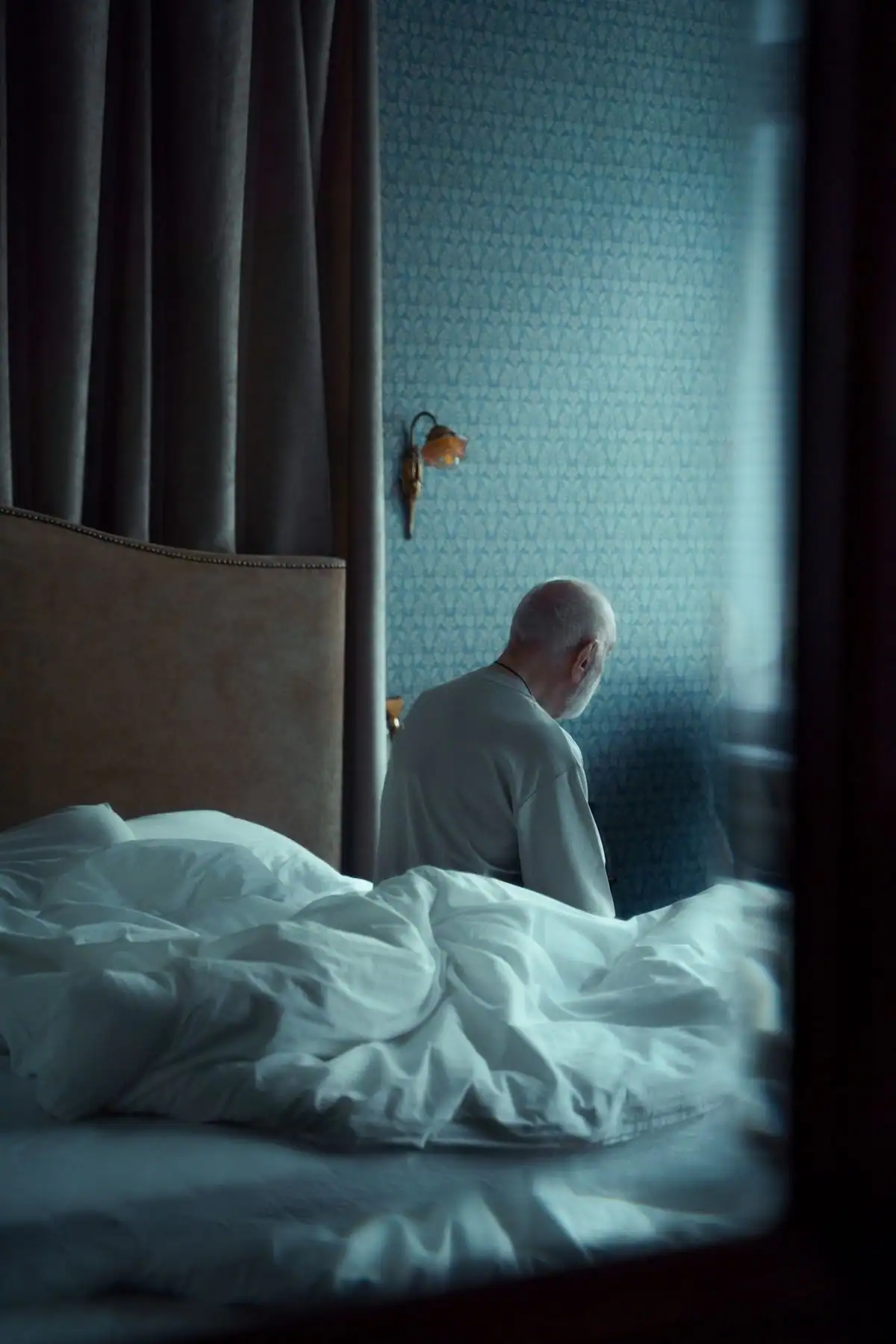 A man sitting on the edge of his bed after waking up